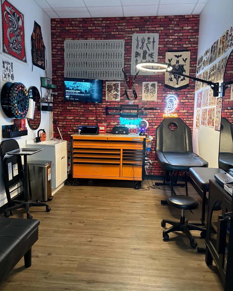 Inside Riverton Tattoos: piercing chair, neon sign and tattoo flash on the brick wall